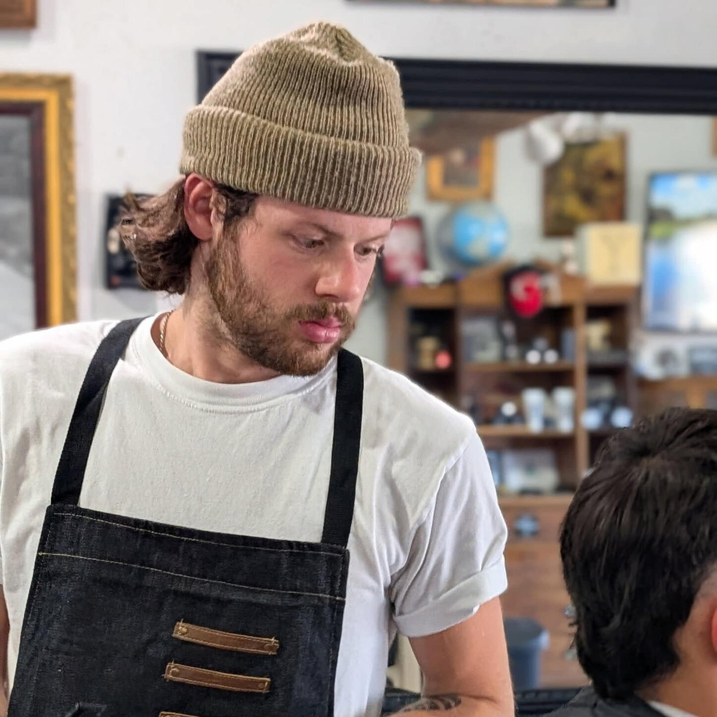 Barber Aidan Redmon delivering a modern men’s haircut at Knucklehead Barbershop in a laid-back, upscale Idaho shop